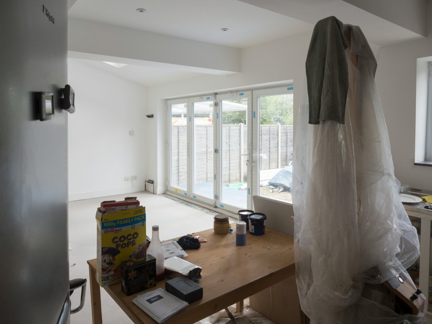 Renovated room with paint supplies and doors opening to backyard.