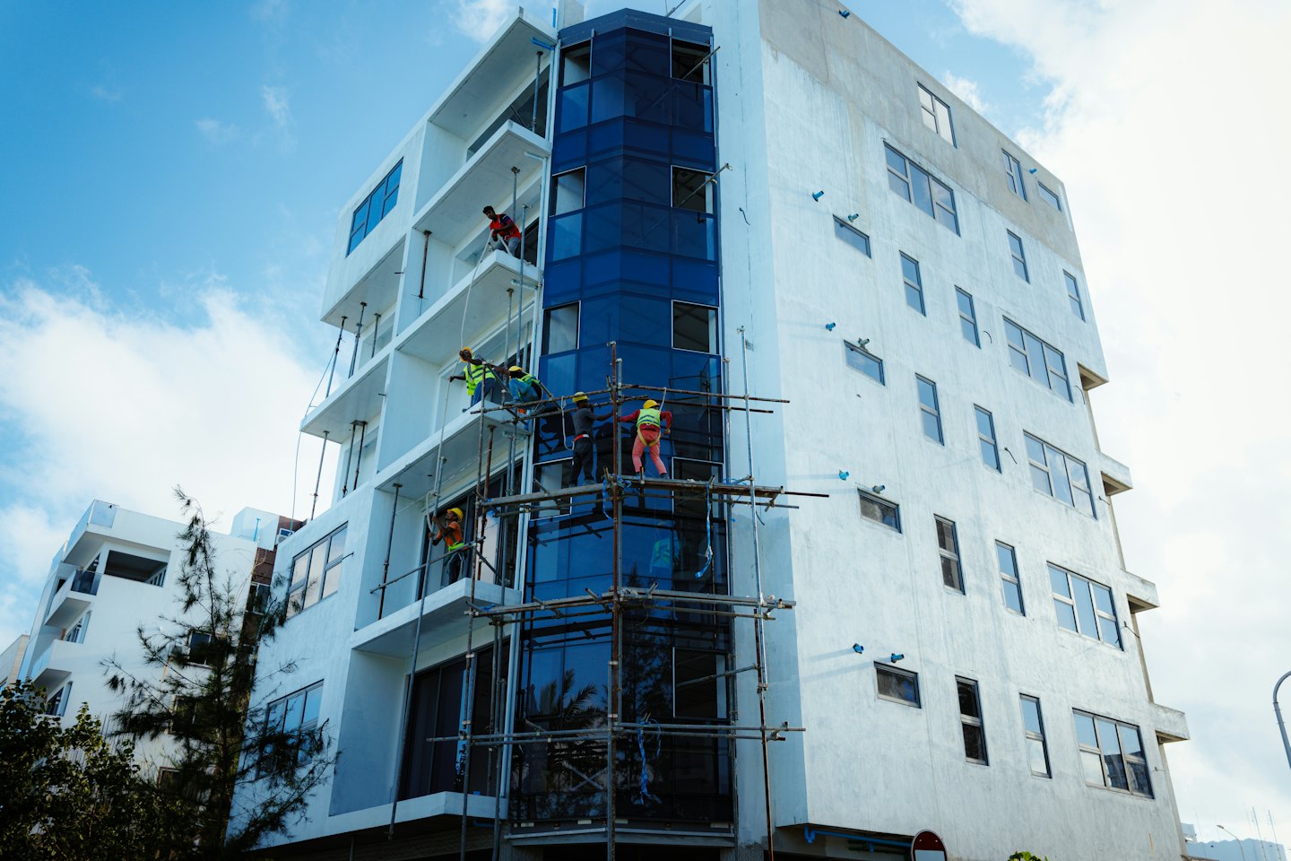 Home Construction workers on scaffolding at a modern white building.