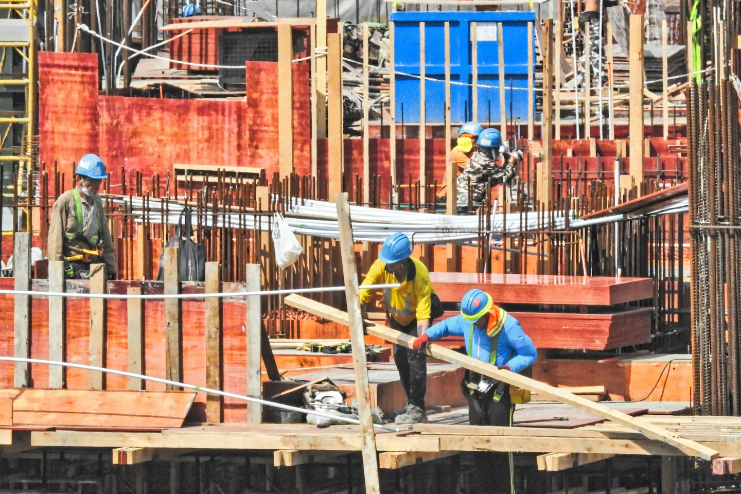 Construction workers assemble a wooden structure at a building site.