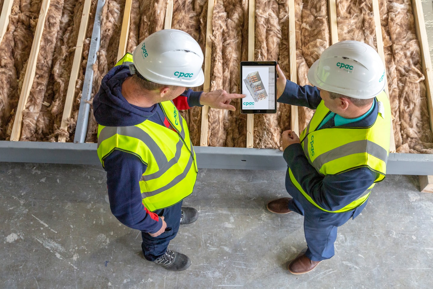Quote Two construction workers discuss a digital tablet at a job site.